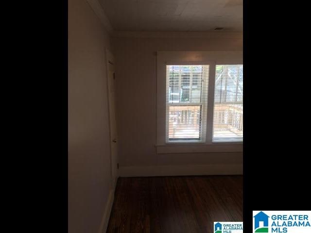 unfurnished room featuring plenty of natural light, wood finished floors, baseboards, and ornamental molding