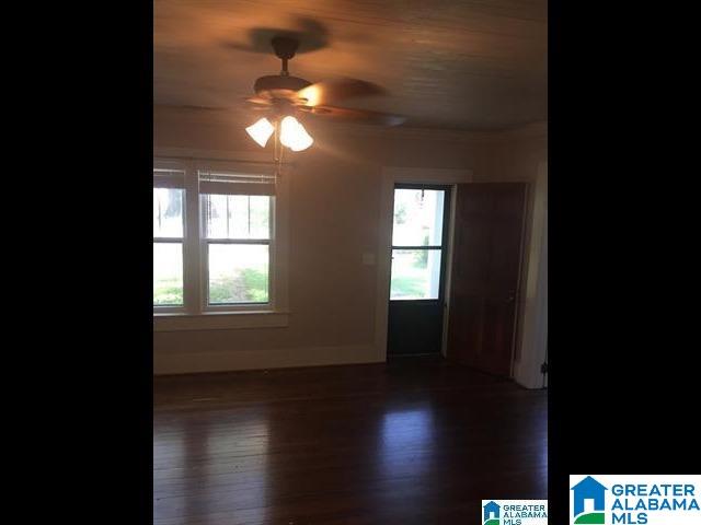 spare room featuring dark wood-type flooring, baseboards, a wealth of natural light, and ceiling fan