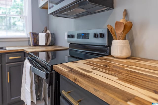 kitchen with stainless steel range with electric stovetop, butcher block countertops, and ventilation hood