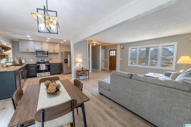 dining room featuring light wood-type flooring, ornamental molding, recessed lighting, baseboards, and a chandelier