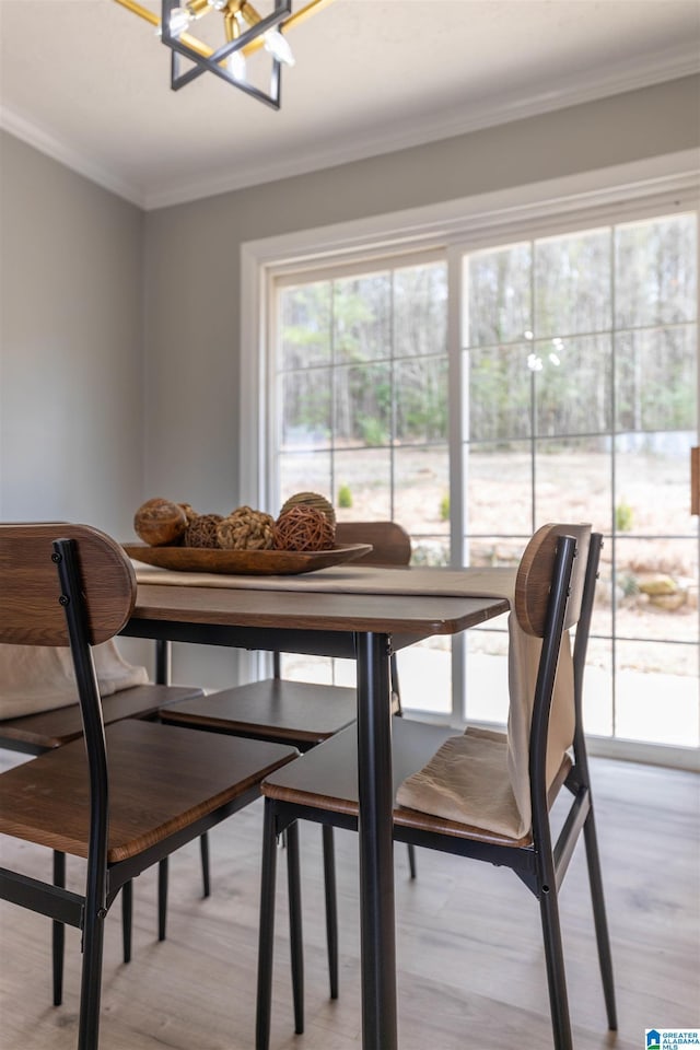 dining area featuring crown molding, a notable chandelier, and light wood-style floors