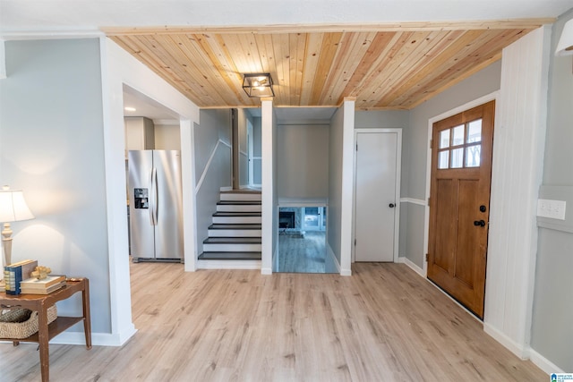 foyer with stairway, wood ceiling, light wood-type flooring, and baseboards