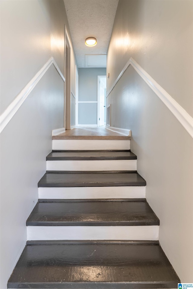 staircase featuring a textured ceiling