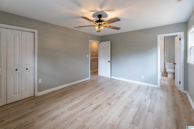 unfurnished bedroom featuring visible vents, wood finished floors, baseboards, and connected bathroom