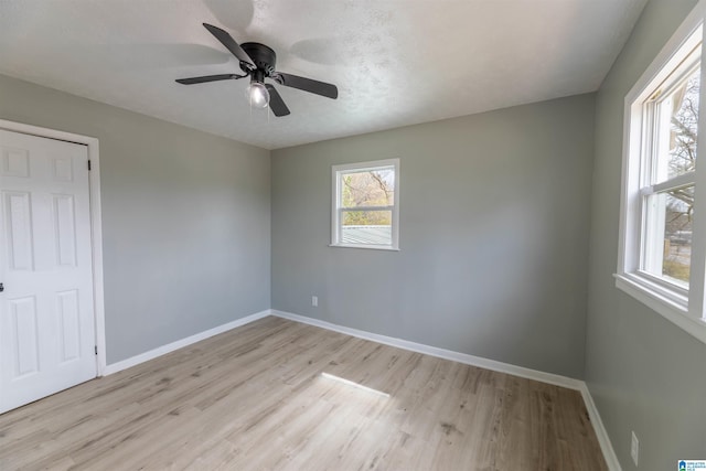 spare room with ceiling fan, baseboards, a textured ceiling, and light wood-style flooring