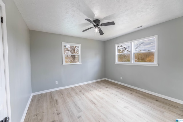 spare room with visible vents, ceiling fan, baseboards, wood finished floors, and a textured ceiling