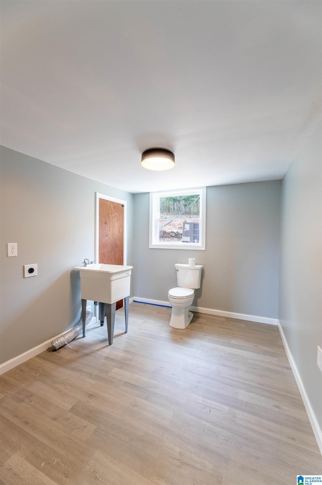 bathroom with baseboards, toilet, and wood finished floors