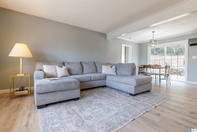 living area featuring beam ceiling, baseboards, light wood-type flooring, and a chandelier