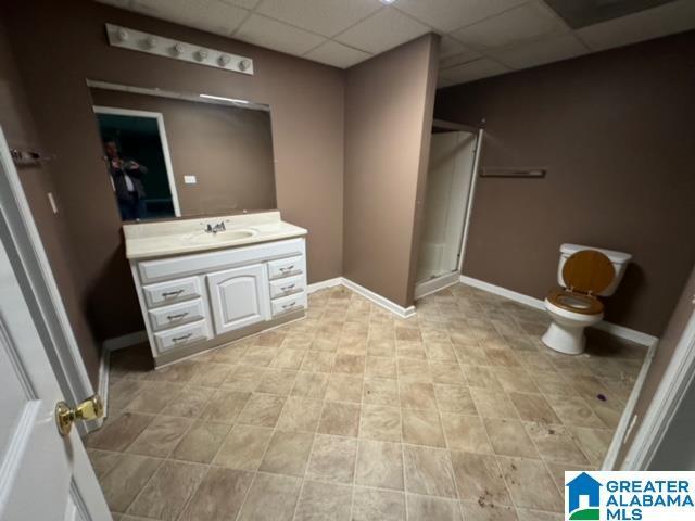 full bath featuring vanity, baseboards, a stall shower, a paneled ceiling, and toilet