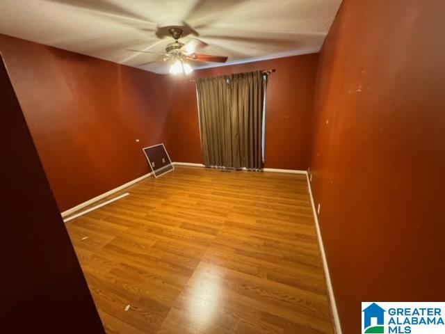 empty room featuring baseboards, light wood-type flooring, and ceiling fan