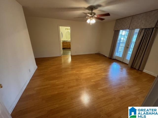 spare room with french doors, baseboards, light wood-type flooring, and a ceiling fan