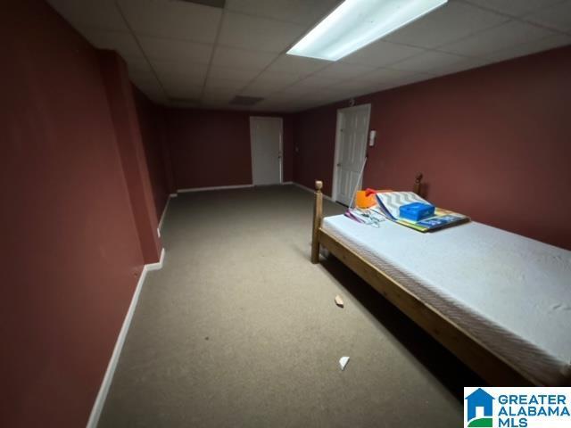 unfurnished bedroom featuring carpet flooring, a paneled ceiling, and baseboards