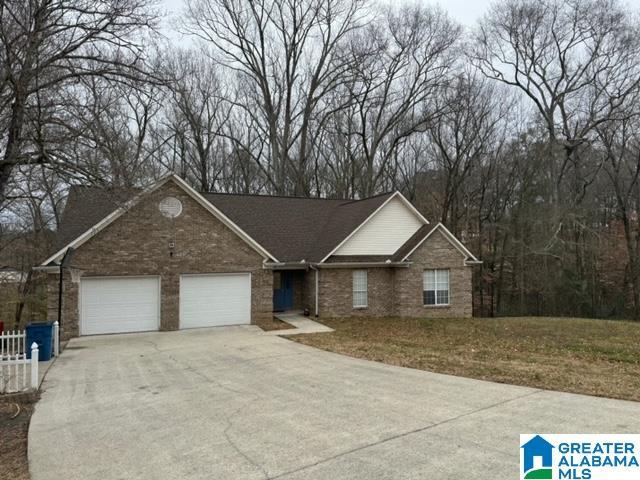 ranch-style house featuring a front yard, fence, concrete driveway, a garage, and brick siding