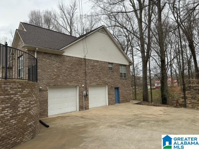 view of side of home featuring brick siding and concrete driveway