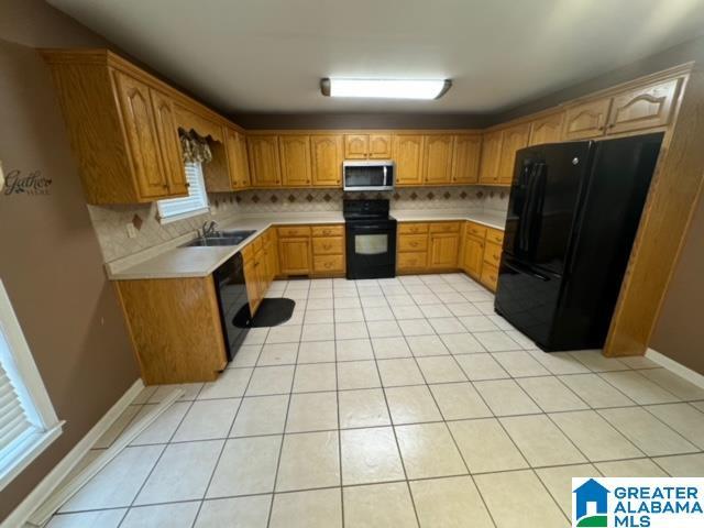 kitchen featuring black appliances, a sink, tasteful backsplash, light countertops, and light tile patterned floors