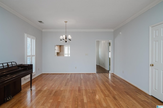 unfurnished room with a notable chandelier, light wood-type flooring, visible vents, and ornamental molding