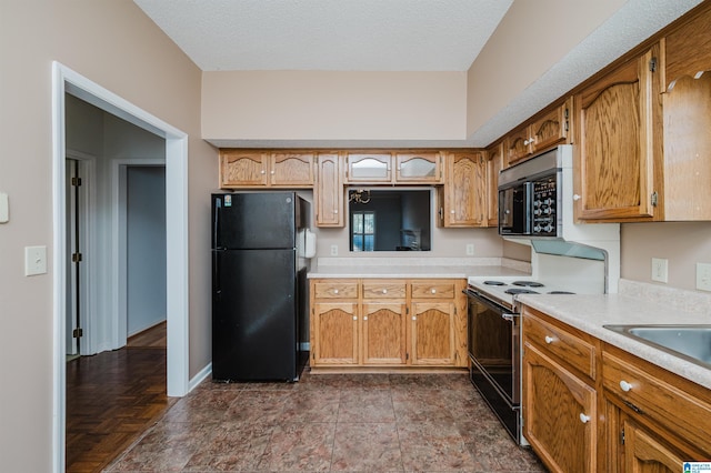 kitchen with black appliances, baseboards, light countertops, brown cabinetry, and a textured ceiling