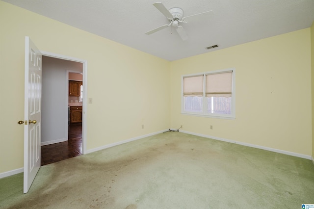 empty room with a ceiling fan, visible vents, carpet floors, and baseboards