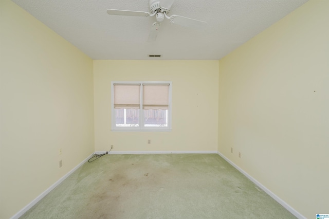 carpeted spare room with visible vents, a textured ceiling, baseboards, and a ceiling fan