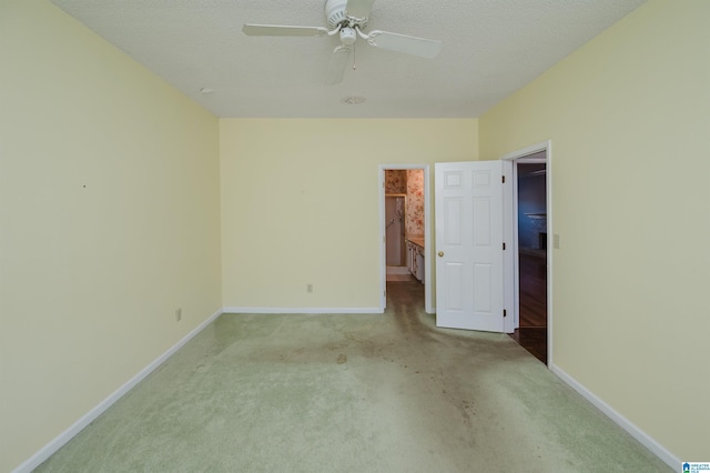 unfurnished bedroom featuring baseboards, light colored carpet, a ceiling fan, and a textured ceiling