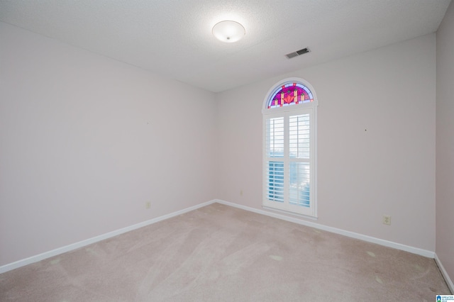 spare room with visible vents, baseboards, light colored carpet, and a textured ceiling