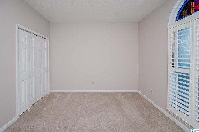 unfurnished bedroom featuring a closet, a textured ceiling, baseboards, and carpet floors