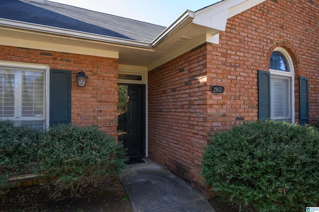 property entrance featuring brick siding and roof with shingles