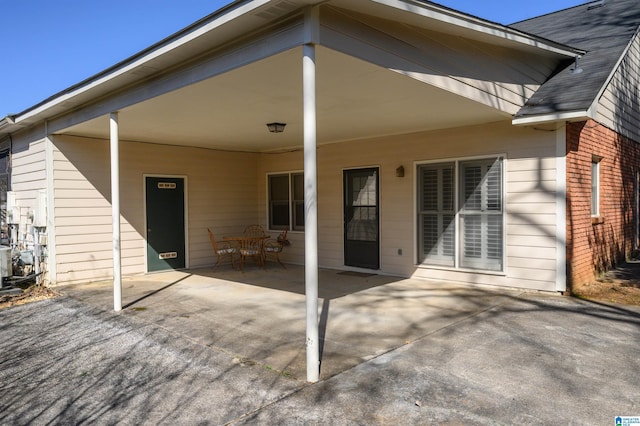 rear view of house featuring an attached carport, concrete driveway, a patio area, and brick siding