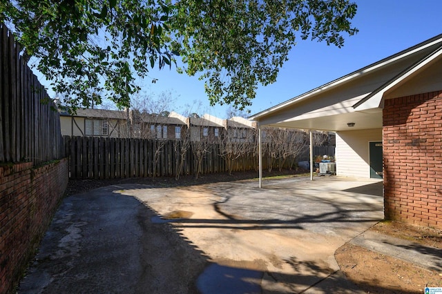 view of yard with an attached carport, driveway, and fence