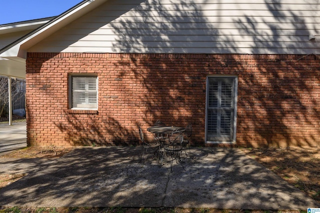 view of property exterior featuring brick siding and a patio