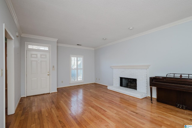 unfurnished living room with crown molding, a brick fireplace, baseboards, and light wood finished floors