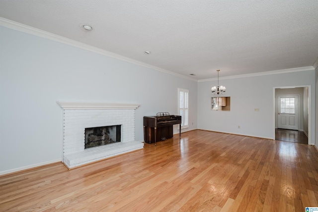 unfurnished living room featuring a brick fireplace, plenty of natural light, light wood-style floors, and a chandelier