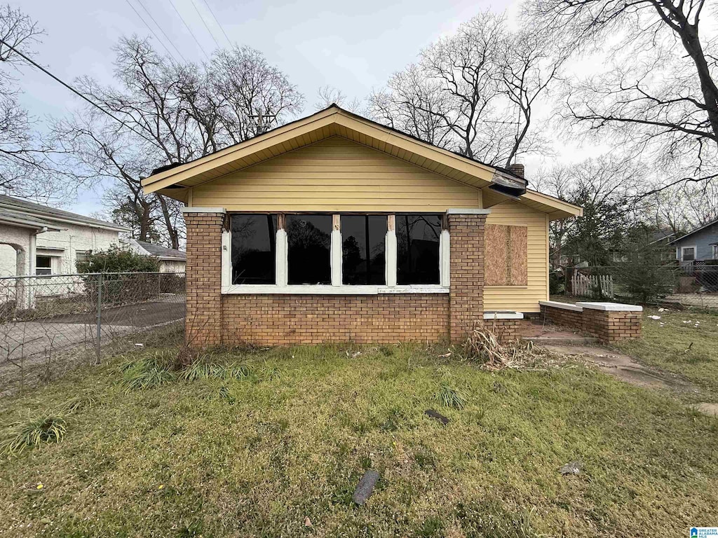 exterior space with brick siding, a chimney, a lawn, and fence