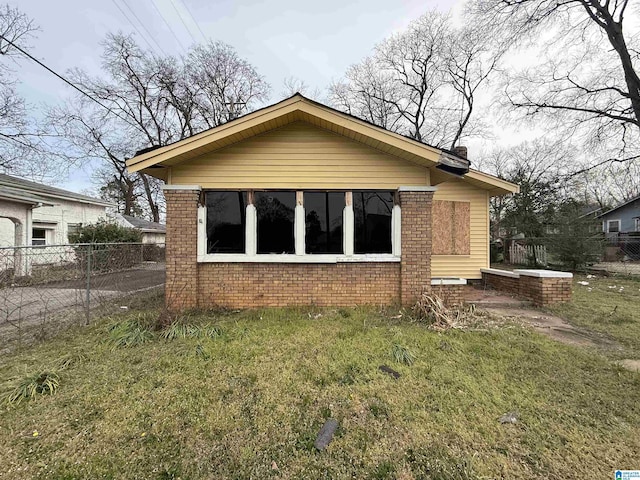 exterior space with brick siding, a chimney, a lawn, and fence