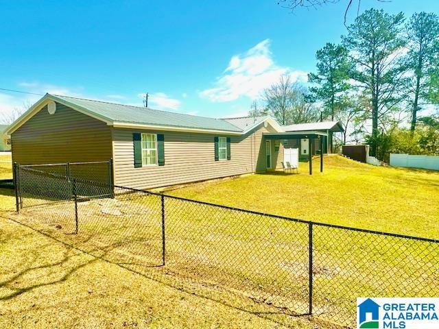 view of property exterior with metal roof, a lawn, a fenced backyard, and a carport