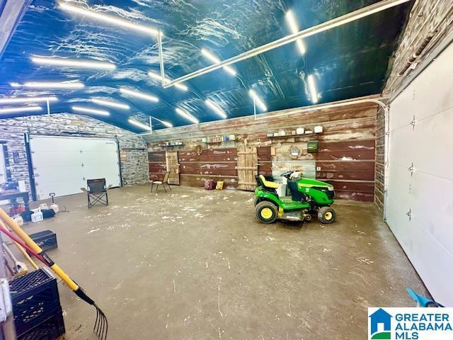 miscellaneous room featuring a garage, concrete flooring, and vaulted ceiling