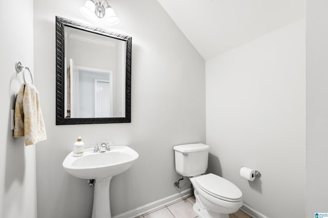 bathroom featuring baseboards, lofted ceiling, a sink, tile patterned floors, and toilet