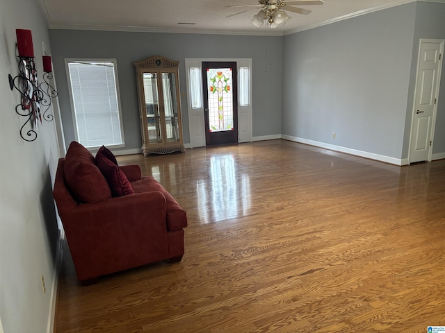 living room featuring baseboards, a ceiling fan, wood finished floors, and crown molding