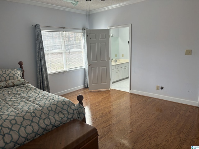 bedroom with baseboards, light wood-style flooring, a sink, a textured ceiling, and crown molding