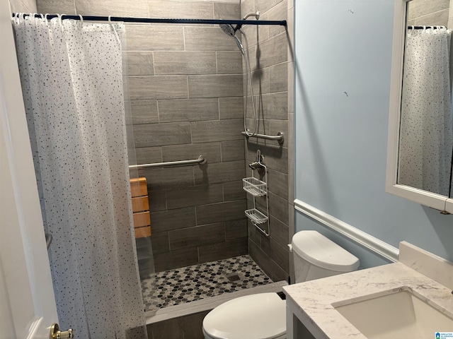 bathroom with vanity, toilet, and tiled shower