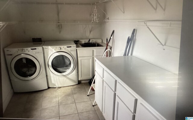 laundry area featuring cabinet space, washing machine and dryer, light tile patterned flooring, and a sink