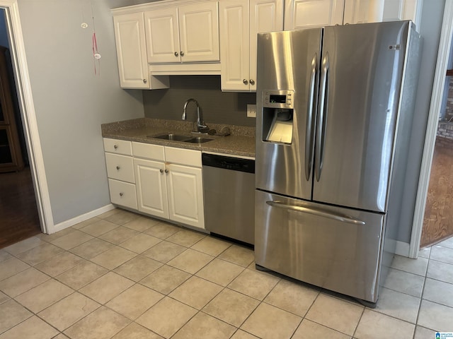 kitchen featuring a sink, stainless steel appliances, white cabinets, light tile patterned floors, and baseboards