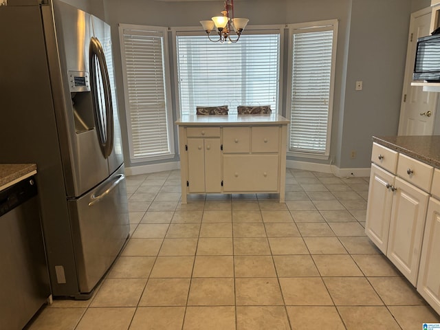 kitchen with light tile patterned floors, baseboards, appliances with stainless steel finishes, and a chandelier