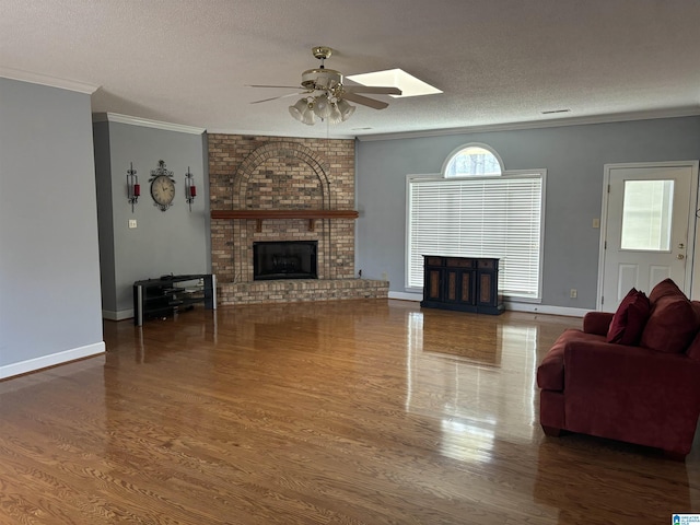 living area with a fireplace, a textured ceiling, wood finished floors, and crown molding