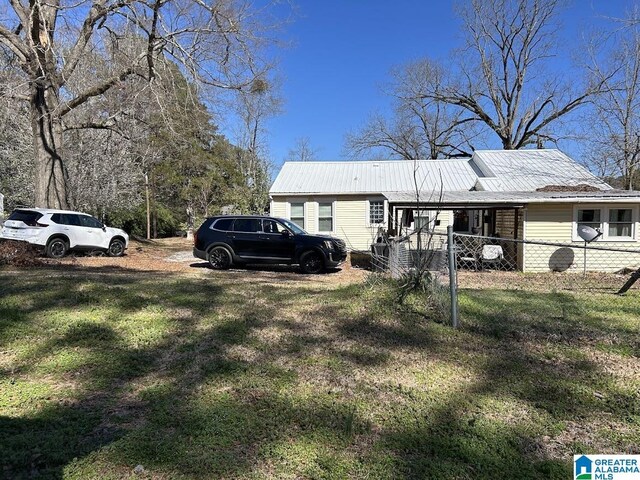 exterior space featuring metal roof, a lawn, and fence