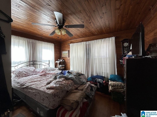 bedroom with ceiling fan, wood finished floors, wooden walls, and wooden ceiling