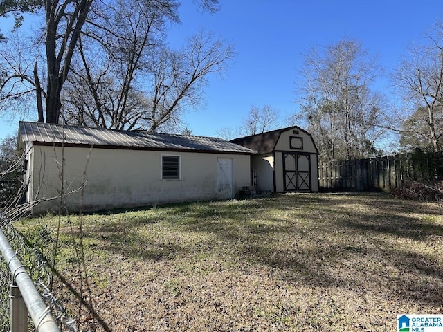 view of home's exterior featuring an outbuilding, a barn, metal roof, and fence