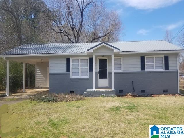 view of front of house with a front yard, metal roof, brick siding, and crawl space