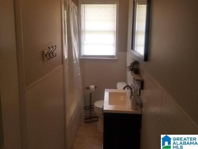 full bathroom featuring tile patterned floors, curtained shower, toilet, and vanity