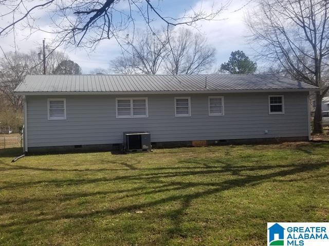 rear view of house with crawl space, central air condition unit, a lawn, and metal roof